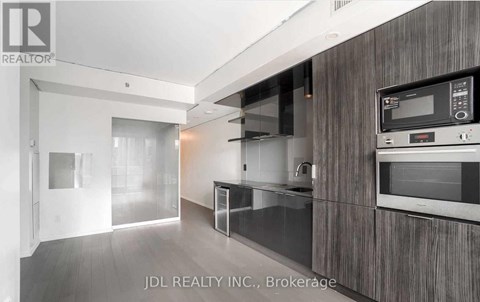 A modern kitchen with dark wood cabinets and stainless steel appliances.