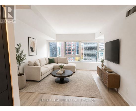 A living room with a couch, coffee table, and a flat screen TV mounted on the wall.