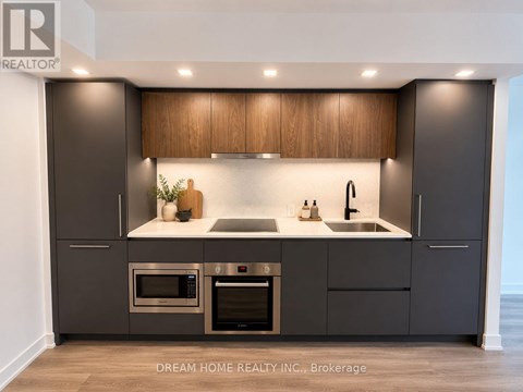 A modern kitchen with dark brown cabinets and stainless steel appliances.
