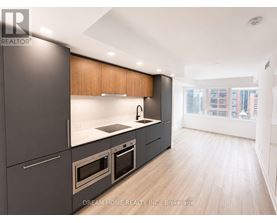 A modern kitchen with dark grey cabinets and wooden accents.