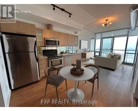 A modern kitchen with a stainless steel refrigerator and a dining table with chairs.