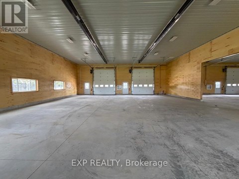 A large empty warehouse space with wooden walls and concrete floor.