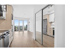 A modern kitchen with a stainless steel refrigerator and wooden flooring.