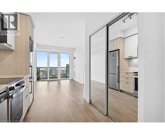 A modern kitchen with a stainless steel refrigerator and wooden flooring.