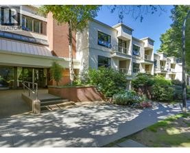 A sunny day at the entrance of a residential building with a realtor sign.
