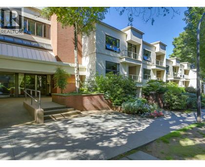 A sunny day at the entrance of a residential building with a realtor sign.