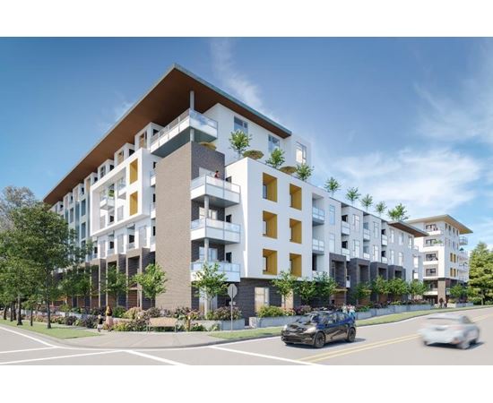 A modern apartment building with cars driving on the street in front.