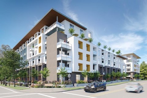 A modern apartment building with cars driving on the street in front.
