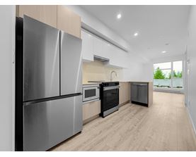 A modern kitchen with a stainless steel refrigerator and wooden flooring.