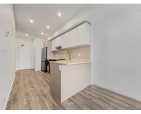 A kitchen with a refrigerator, sink, and cabinets.