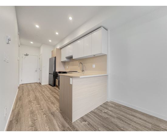 A kitchen with a refrigerator, sink, and cabinets.