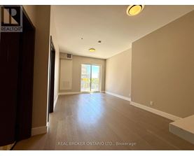 A spacious room with wooden floors and a large window.