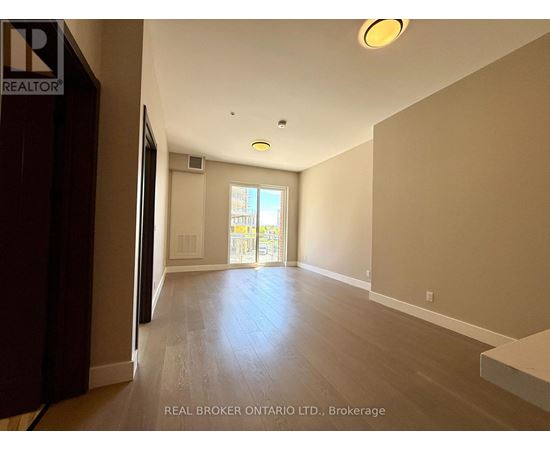 A spacious room with wooden floors and a large window.