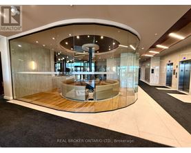 A modern office lobby with a circular glass wall and a wooden floor.