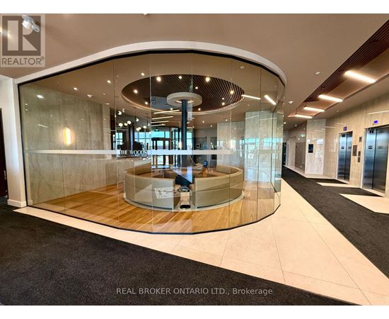 A modern office lobby with a circular glass wall and a wooden floor.