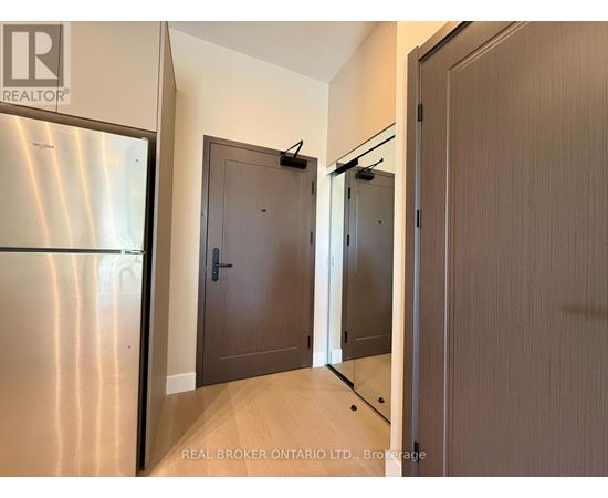 A brokerage sign is on the wall above a stainless steel refrigerator in a modern kitchen.