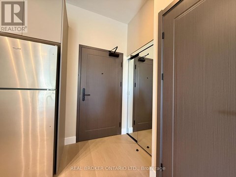 A brokerage sign is on the wall above a stainless steel refrigerator in a modern kitchen.