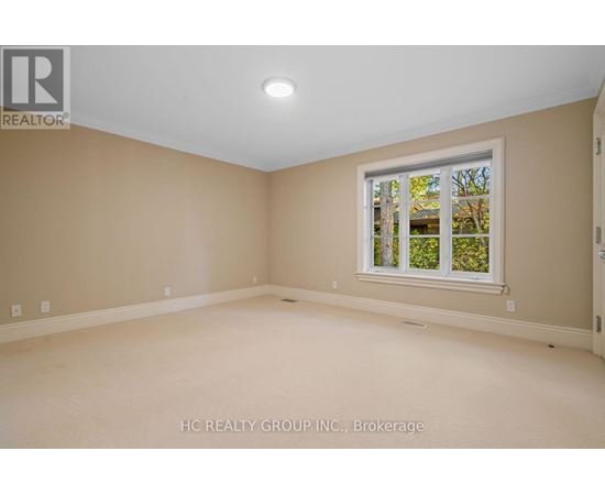 A room with a window showing trees and a wall with a logo that says REALTOR.