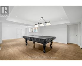A pool table in a room with wooden flooring and white walls.