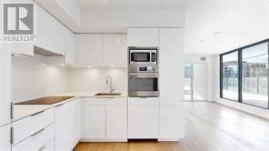 A modern kitchen with white cabinets and a wooden floor.