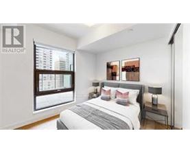 A bedroom with a large bed and a window overlooking a cityscape.
