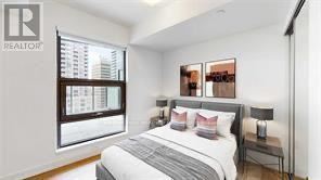 A bedroom with a large bed and a window overlooking a cityscape.