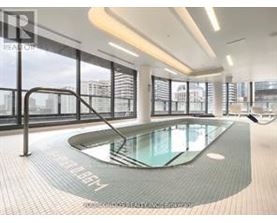 A modern indoor swimming pool with a glass bottom and a metal railing.