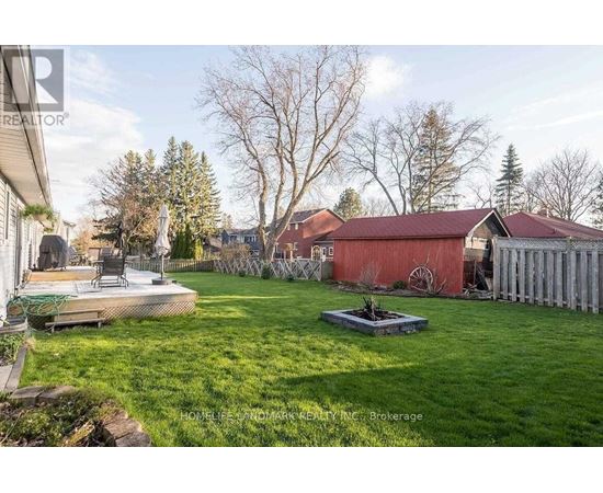 A backyard with a red house and a green lawn.