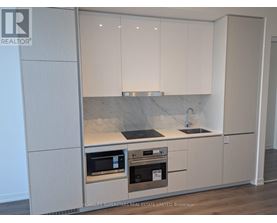 A kitchen with white cabinets and a marble countertop.