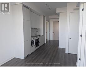 A modern kitchen with white cabinets and a wooden floor.