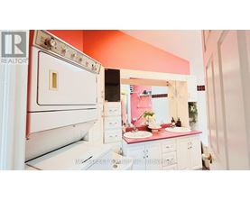 A white refrigerator is in a kitchen with pink walls.