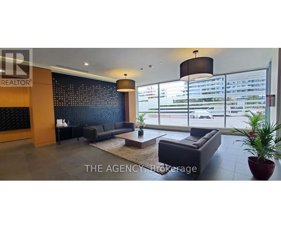 A large, modern living room with a dark blue couch and a large window with a view of a parking lot.