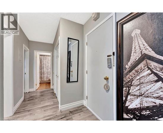 A hallway with a door on the right and a picture of the Eiffel Tower on the wall.