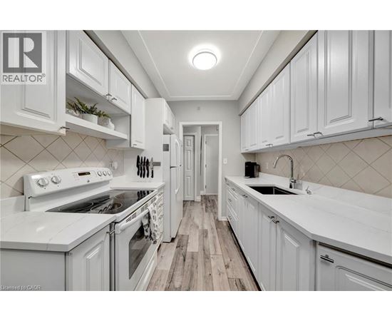 A white kitchen with a wood floor and white cabinets.