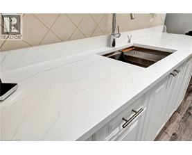 A white marble countertop with a sink and a black laptop on it.
