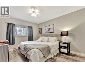 A bedroom with a bed, nightstand, and a window with curtains.