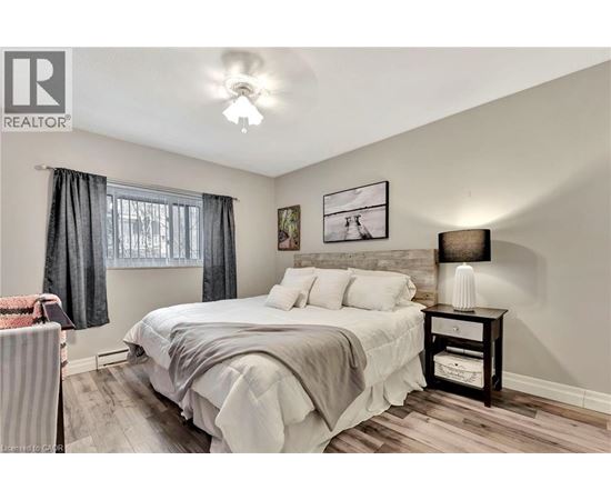 A bedroom with a bed, nightstand, and a window with curtains.