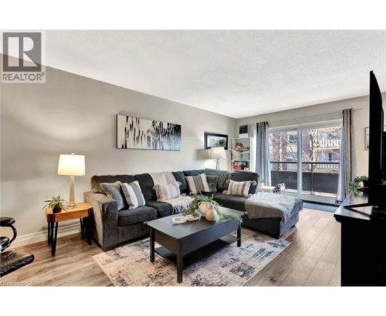 A living room with a grey couch, a coffee table, and a painting on the wall.