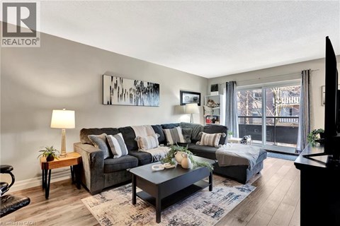 A living room with a grey couch, a coffee table, and a painting on the wall.