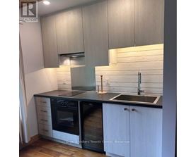 A modern kitchen with white cabinets and black countertops.