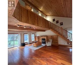 A large open living room with wood floors and a staircase.