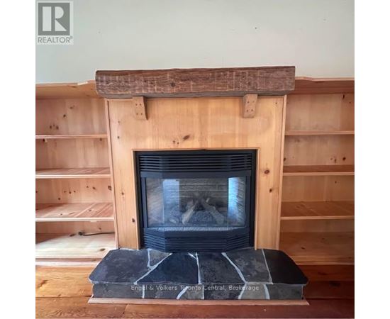 A fireplace with a wooden mantle and a stone base.