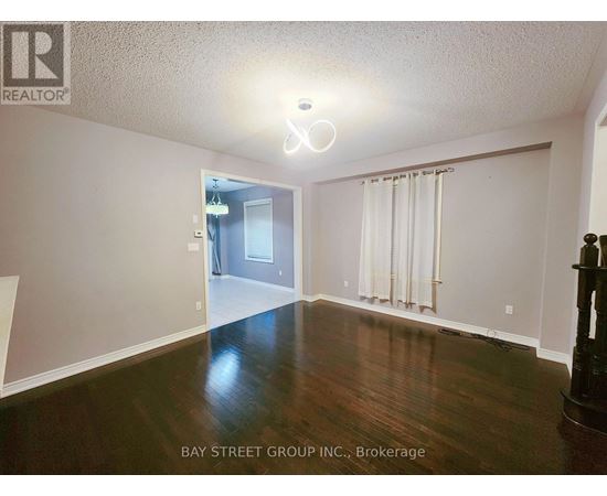 A spacious room with wooden floors and a doorway leading to another room.