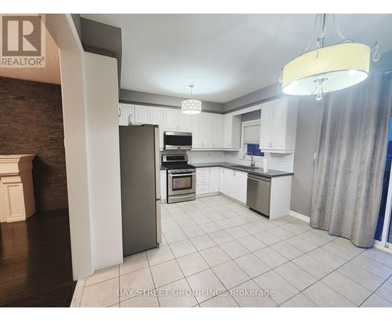 A kitchen with white cabinets and a refrigerator.
