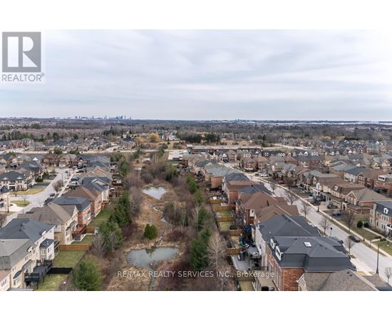 A bird's eye view of a residential area with houses and a pond.