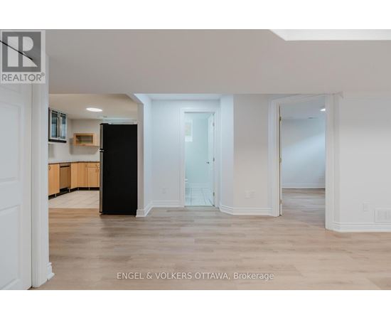 A spacious, empty room with a black cabinet and a white door.