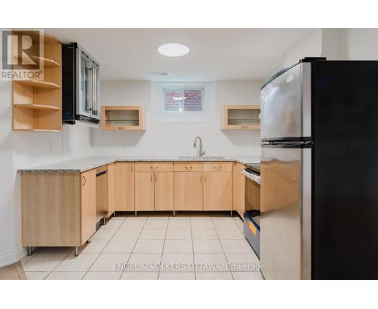 A kitchen with wooden cabinets and a black refrigerator.