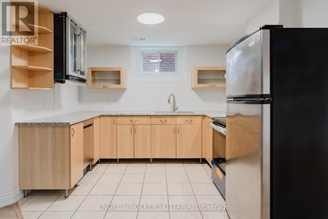 A kitchen with wooden cabinets and a black refrigerator.