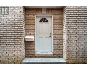A white door with a glass window in the middle is set in a brick wall.