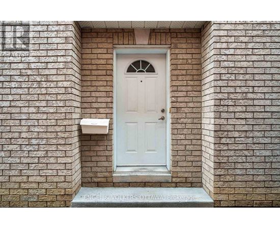 A white door with a glass window in the middle is set in a brick wall.